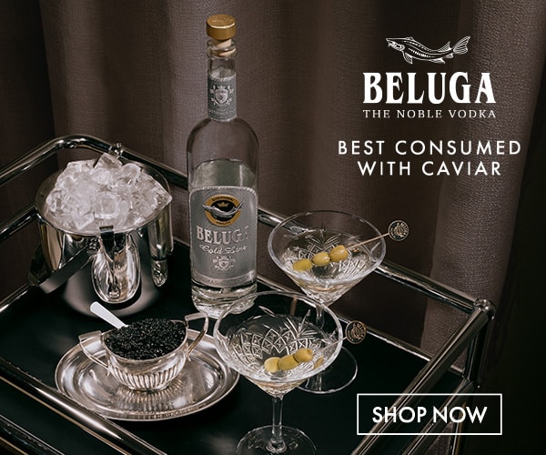 Still life with Beluga vodka bottle, caviar, and two cocktail glasses on a bar cart; caption reads 'Best consumed with caviar' and a 'Shop Now' call to action.
